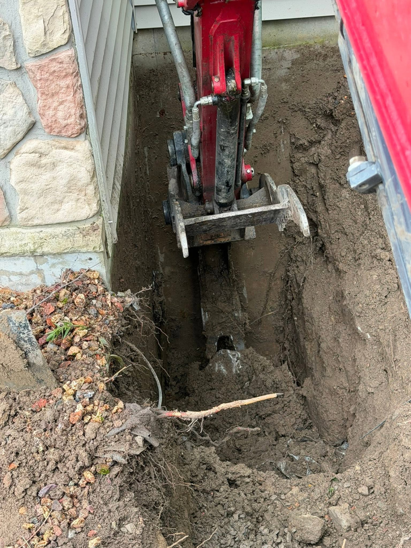 Narrow utility trench dug tight to a home foundation