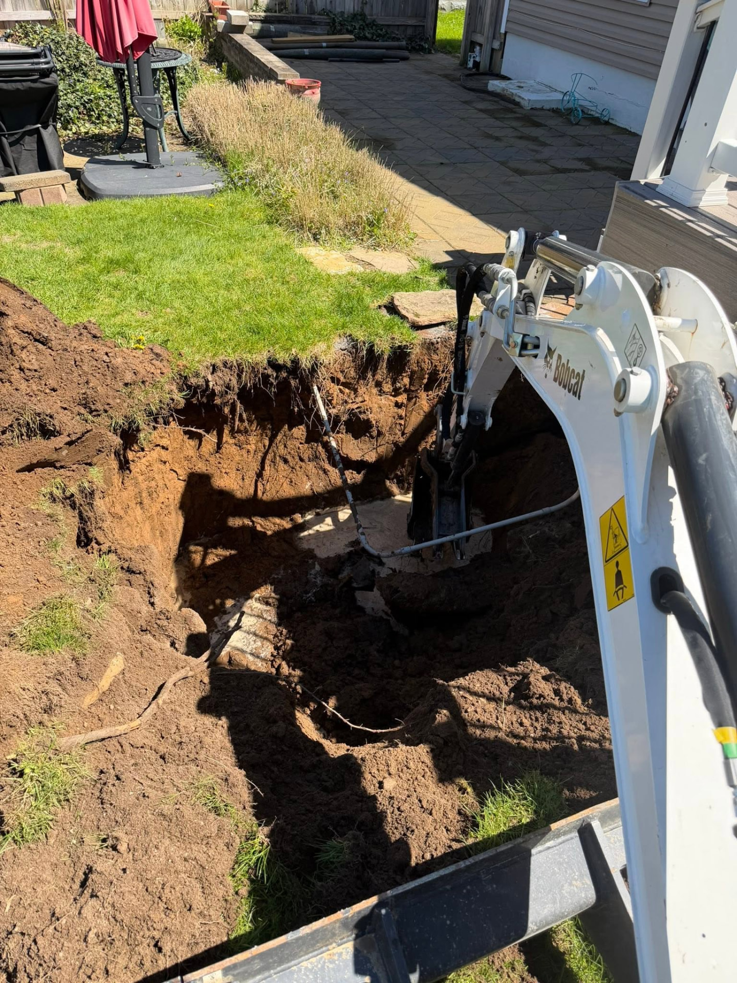 Excavator digging alongside a backyard patio